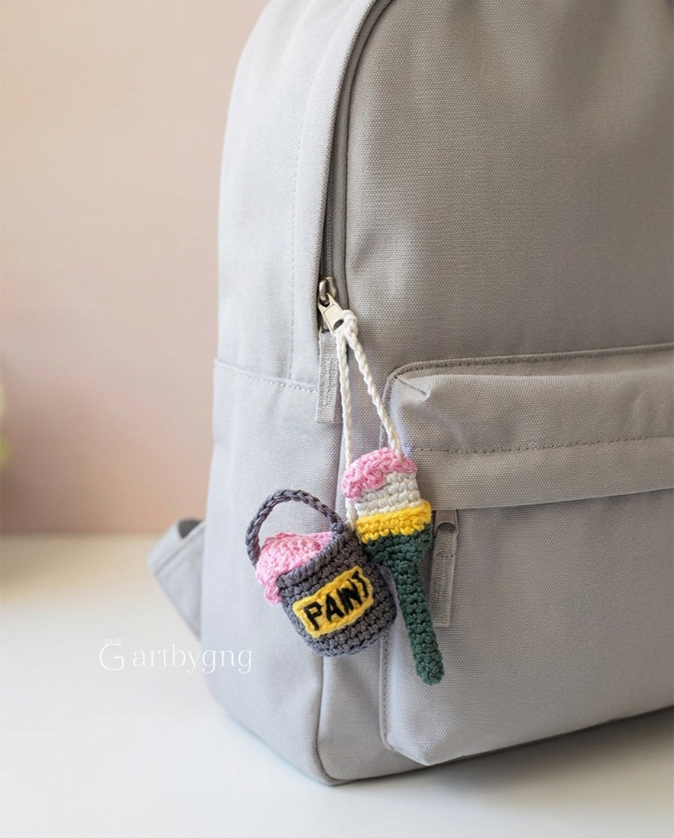 Finished paint brush and paint can charms clipped to a backpack zipper